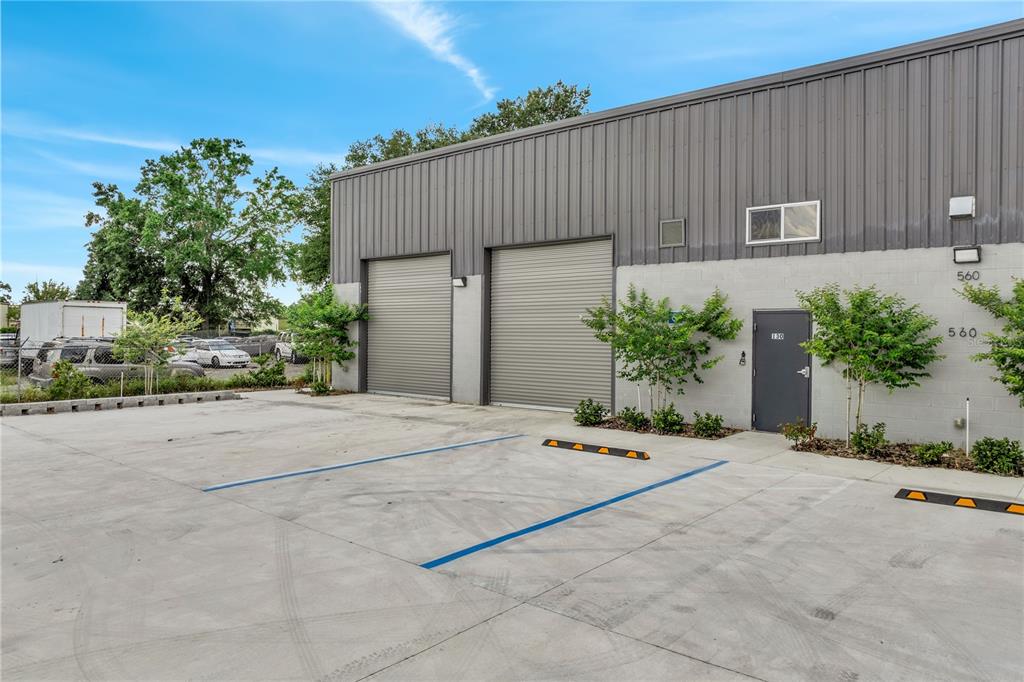 The exterior of a commercial warehouse building features two roll-up doors and a pedestrian entrance — 560 BARRY STREET, ORLANDO, FL