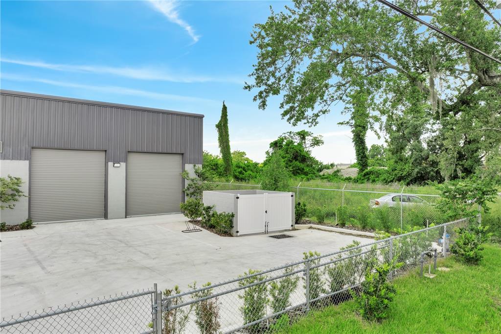 A gray metal warehouse building features two roll-up doors and a white dumpster enclosure — 560 BARRY STREET, ORLANDO, FL