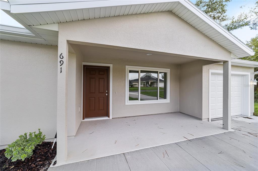 The exterior of a house features a covered porch, a brown front door, and a garage — 715 NE 130TH COURT, SILVER SPRINGS, FL