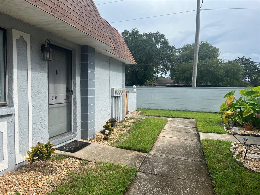 A concrete walkway leads to the front door of a light blue house with gravel landscaping — 5100 70TH PLACE N UNIT 5100, PINELLAS PARK, FL