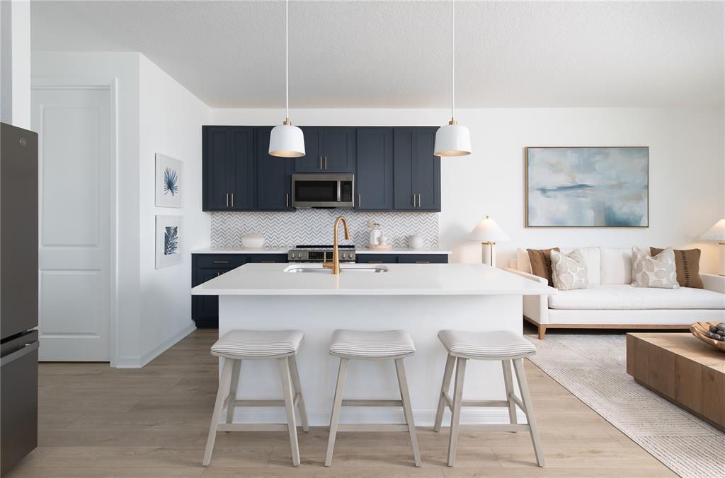 A modern kitchen features dark blue cabinets, a white island with bar stools, and light flooring — 7536 DEER VALLEY CIRCLE, TAMPA, FL