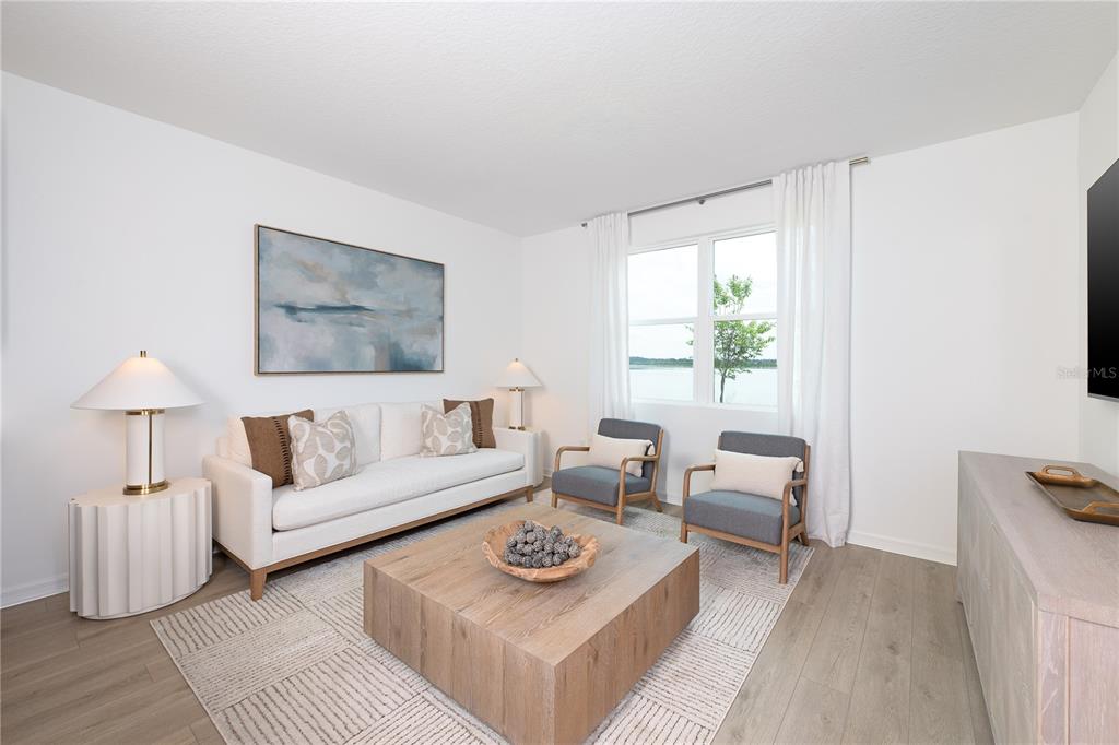 A bright living room features a white sofa, two gray chairs, and a wooden coffee table — 7536 DEER VALLEY CIRCLE, TAMPA, FL