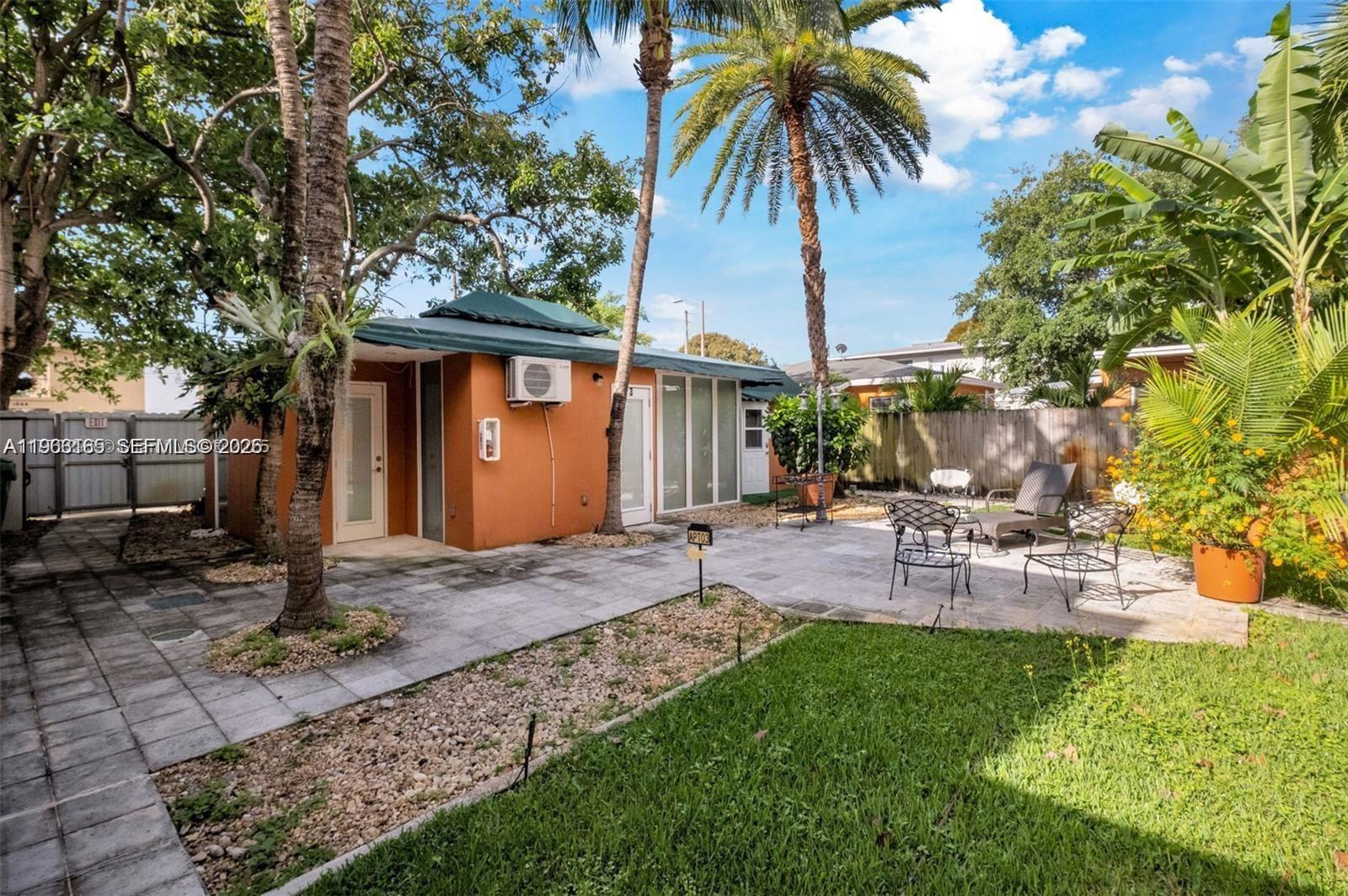 A small orange building with a patio, palm trees, and outdoor furniture in a yard — 1033 NW 6th St, Miami FL 33136, MIAMI, FL