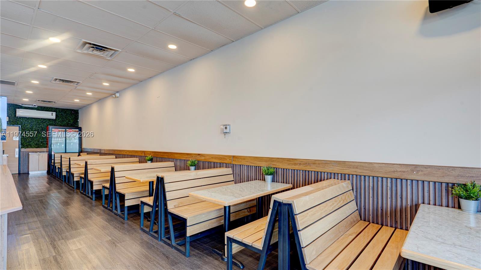 A restaurant interior features rows of wooden booth seating with marble-topped tables along a wall — Kendall Miami, Miami FL 33193, MIAMI, FL