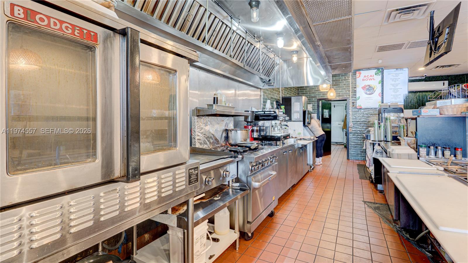 A commercial kitchen features stainless steel appliances, a tiled floor, and a ventilation hood — Kendall Miami, Miami FL 33193, MIAMI, FL