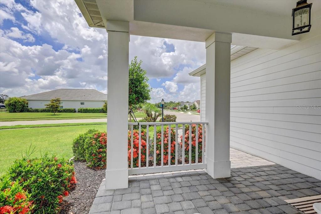 A covered porch features white columns, a white railing, and gray stone pavers — 10606 MORNING MARSH LANE, PARRISH, FL