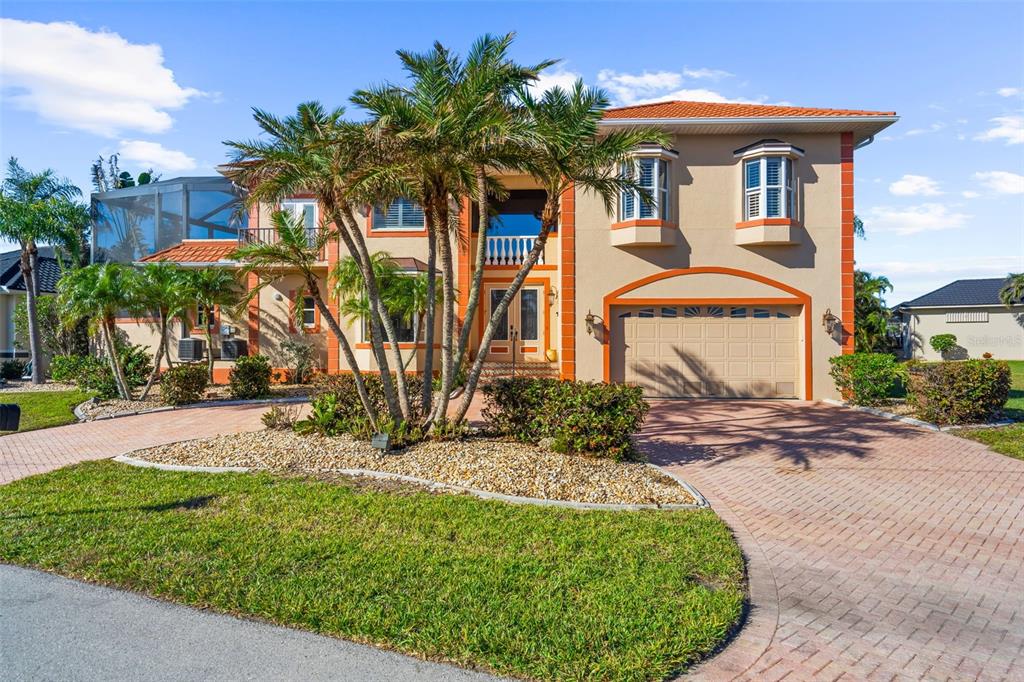 A two-story stucco house with a screened-in lanai, palm trees, and a brick paver driveway — 3805 SABA COURT, PUNTA GORDA, FL