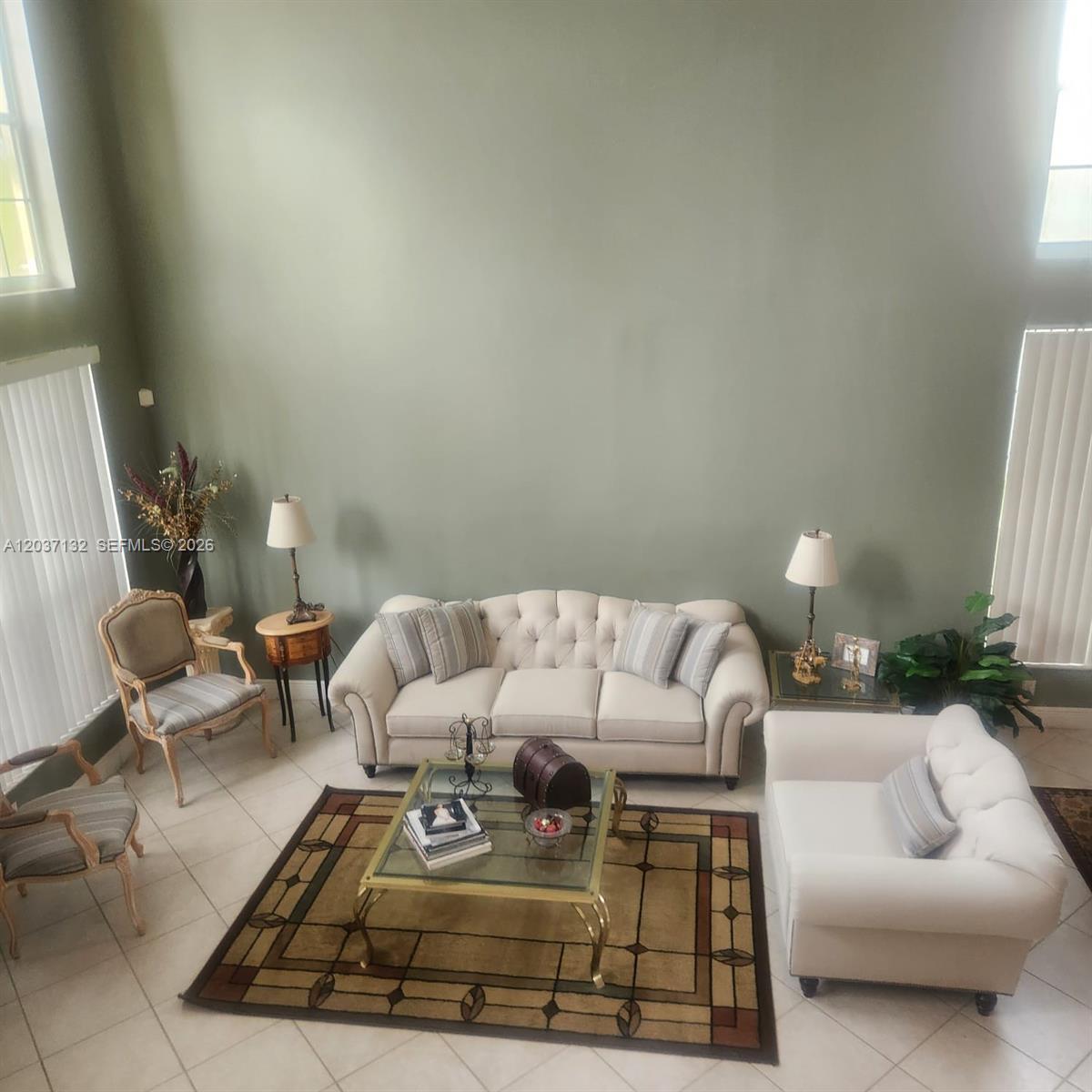 A high-ceilinged living room features a beige tufted sofa, matching armchair, and a glass coffee table — 17958 SW 36th St, Miramar FL 33029, MIRAMAR, FL