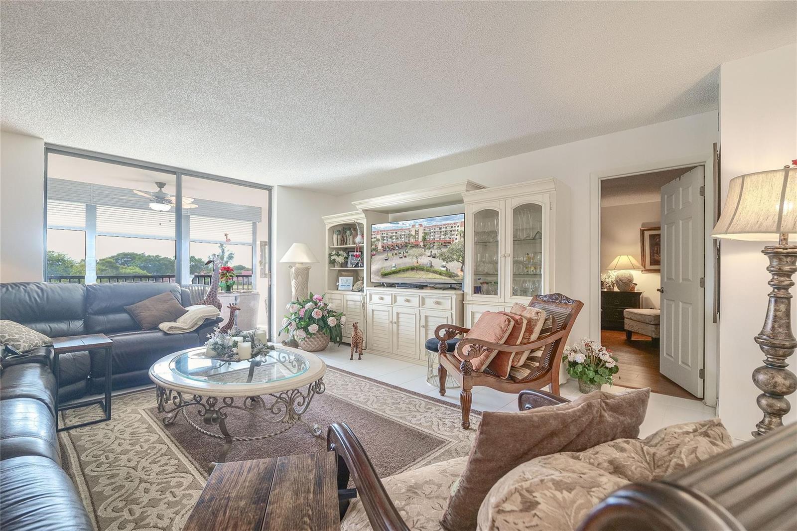 A living room features a leather sofa, a glass coffee table, and a media center — 3591 Environ Boulevard # 401, Lauderhill FL 33319, LAUDERHILL, FL