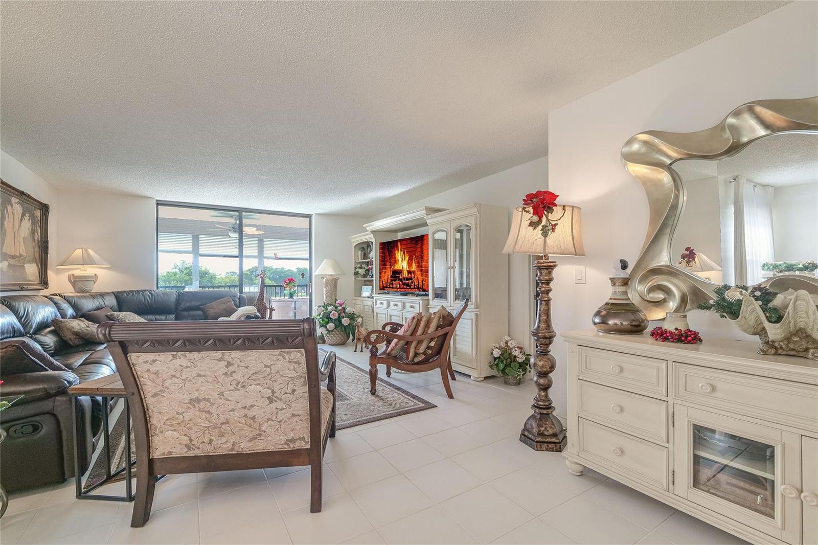 A living room features a dark leather sectional, a floral armchair, and a white entertainment center — 3591 Environ Boulevard # 401, Lauderhill FL 33319, LAUDERHILL, FL