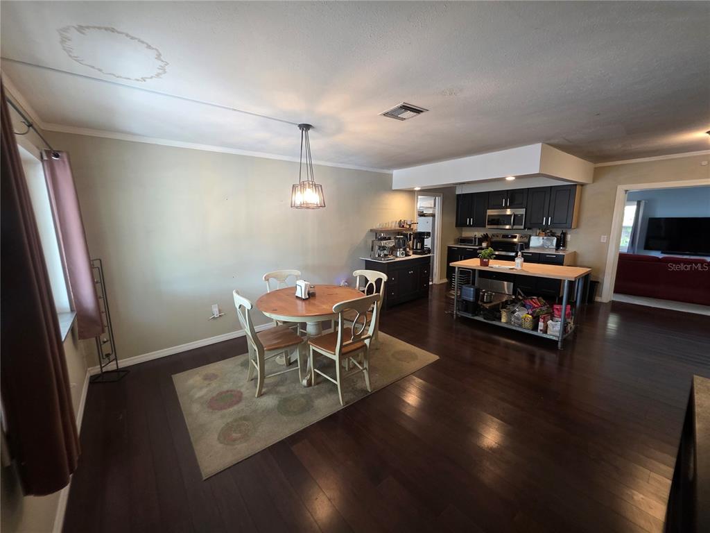 A dining area with a round table and chairs sits adjacent to an open kitchen — 1015 RHODES AVENUE, SARASOTA, FL