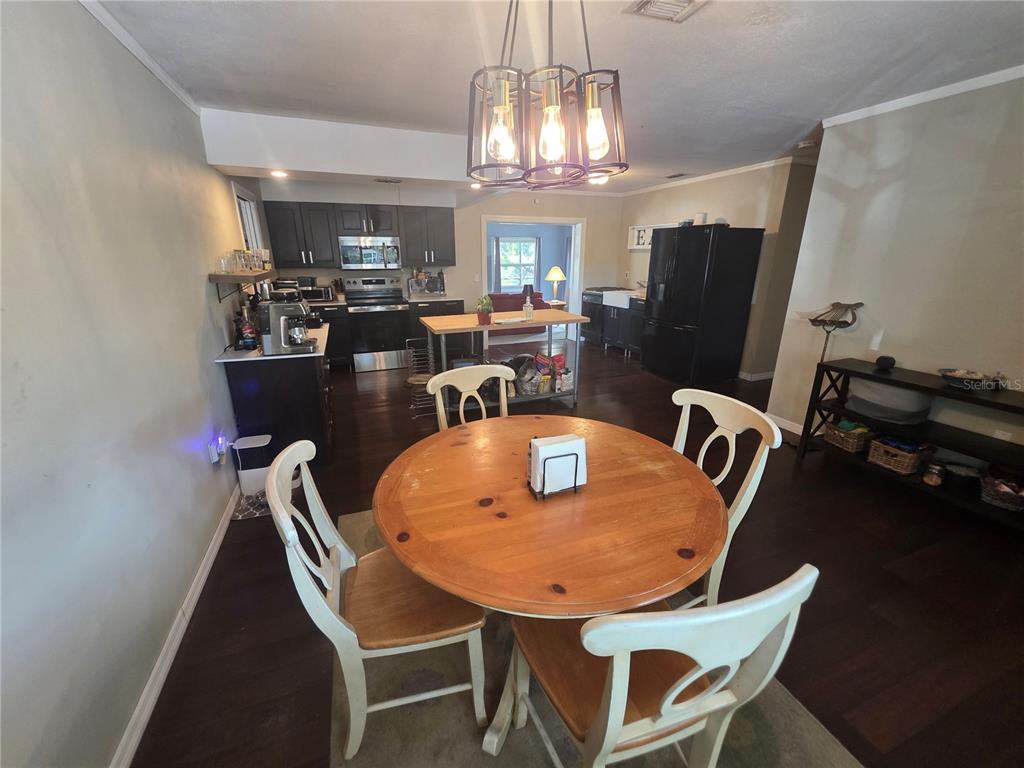 A dining area with a round wooden table sits in front of an open kitchen — 1015 RHODES AVENUE, SARASOTA, FL