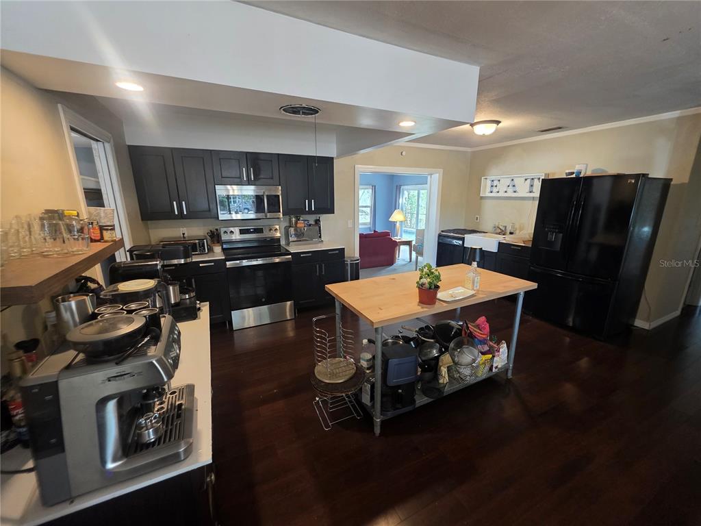 A kitchen features dark cabinets, stainless steel appliances, a wooden island, and dark wood flooring — 1015 RHODES AVENUE, SARASOTA, FL