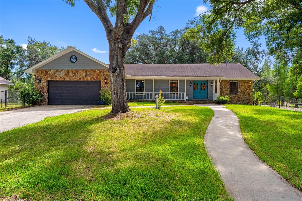 A single-story house with a stone facade, gray siding, and a teal front door — 11109 WINN ROAD, RIVERVIEW, FL