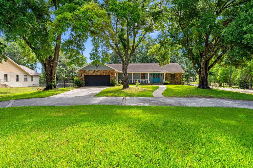 A single-story house with a stone facade, a dark garage, and a bright blue front door — 11109 WINN ROAD, RIVERVIEW, FL
