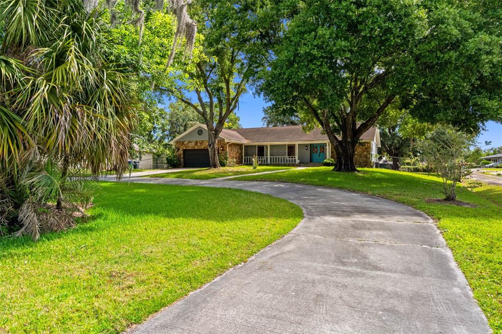 A single-story house with a stone facade and a curved concrete driveway sits among trees — 11109 WINN ROAD, RIVERVIEW, FL