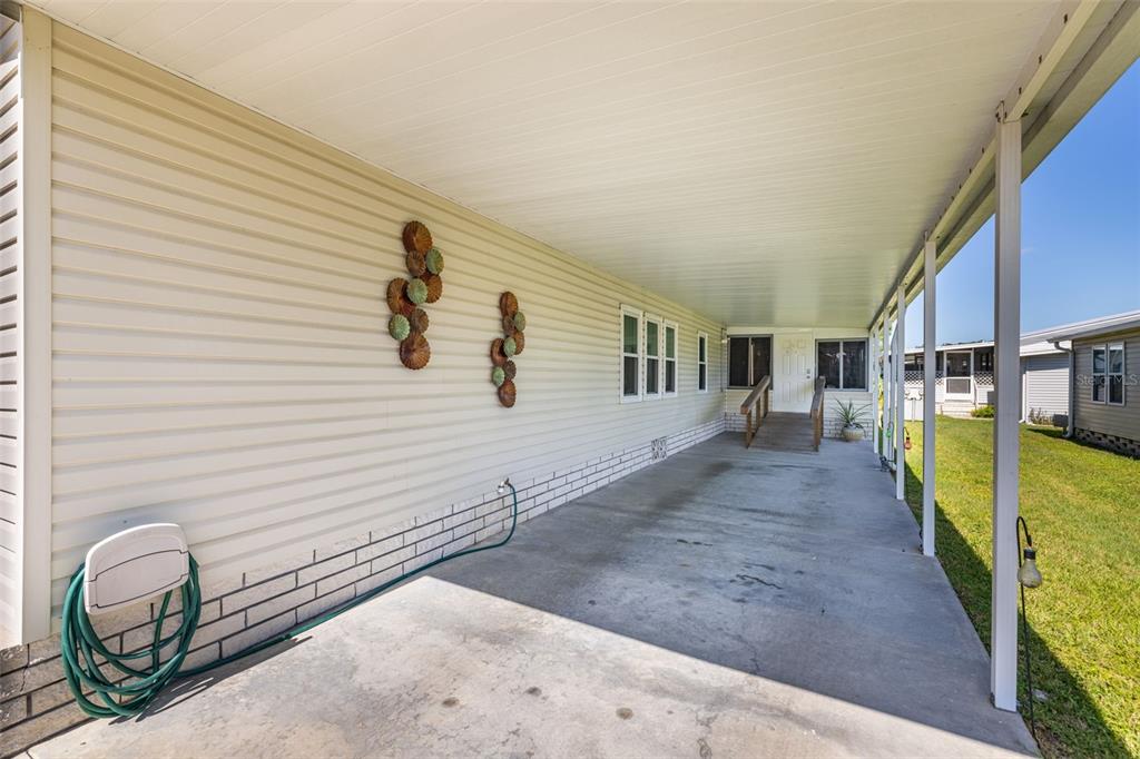 A concrete carport with a ramp leading to the entrance of a light-colored mobile home — 3111 SHORT LEAF STREET, WESLEY CHAPEL, FL