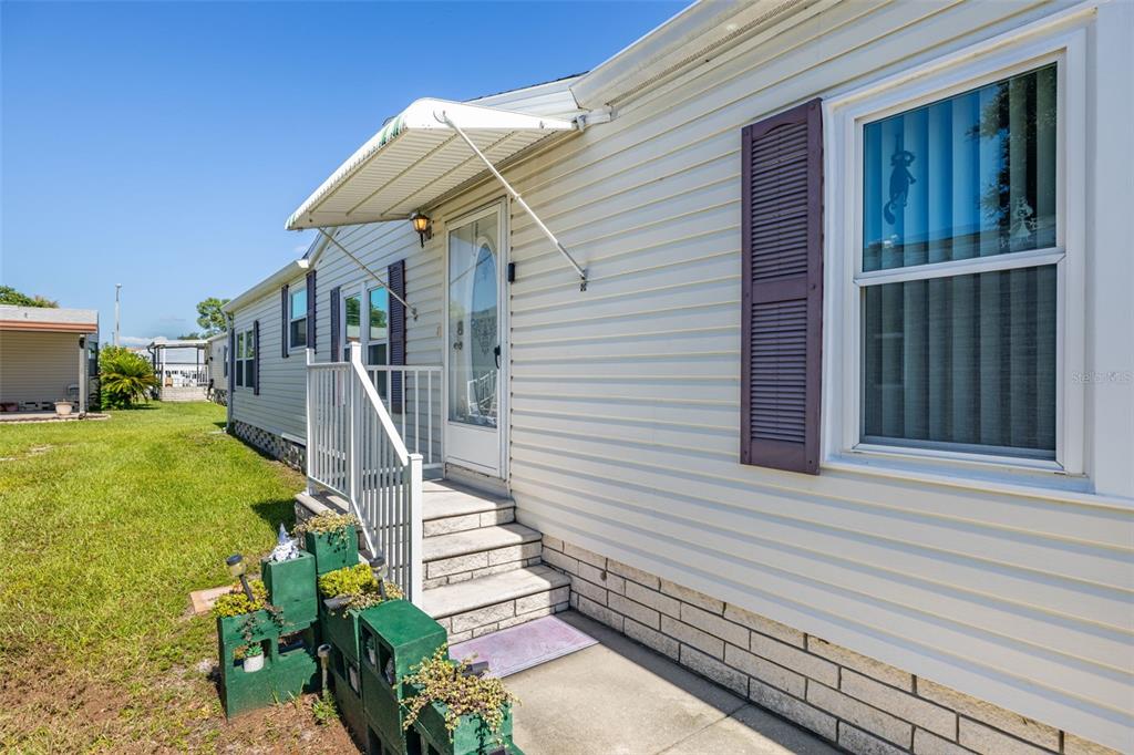 Exterior view of a mobile home with light siding, dark shutters, and a small porch — 3111 SHORT LEAF STREET, WESLEY CHAPEL, FL