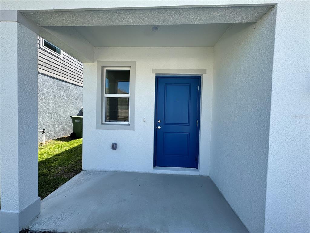 A covered concrete porch features a blue front door and a single window — 405 KAYDEN COVE, WINTER HAVEN, FL