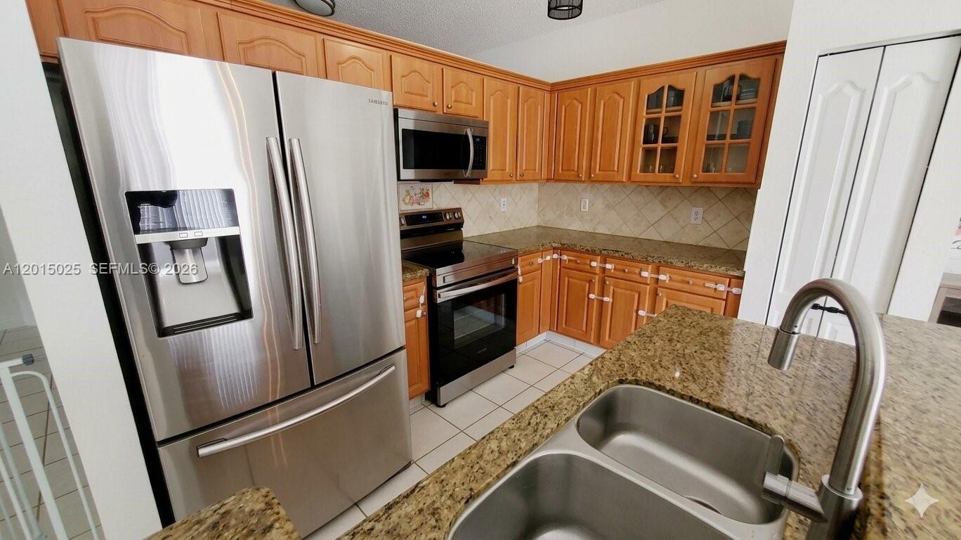 A kitchen features wood cabinets, granite countertops, stainless steel appliances, and a double-basin sink — 10273 SW 162nd Ct, Miami FL 33196, MIAMI, FL
