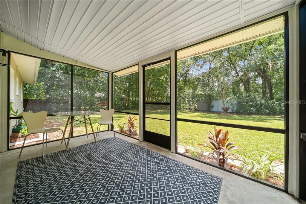 A screened-in porch with a concrete floor, a patterned rug, and views of a backyard — 3164 SE 11TH STREET, OCALA, FL