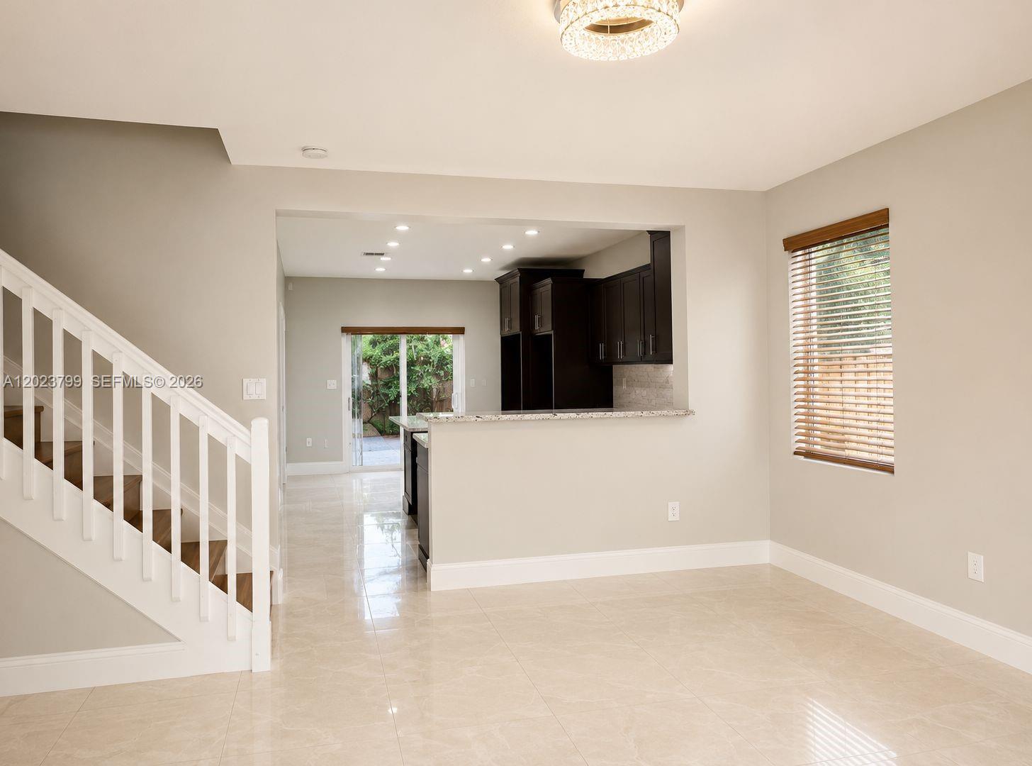 A bright room features a staircase, a kitchen with dark cabinets, and tile flooring — 28407 SW 129th Pl, Homestead FL 33033, HOMESTEAD, FL