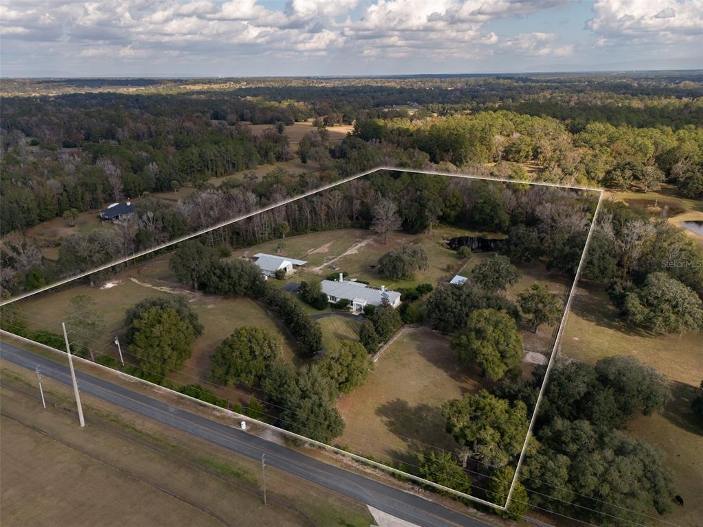 An aerial view shows a house and outbuildings on a large, fenced, wooded lot — 7575 NW 90TH AVENUE, OCALA, FL
