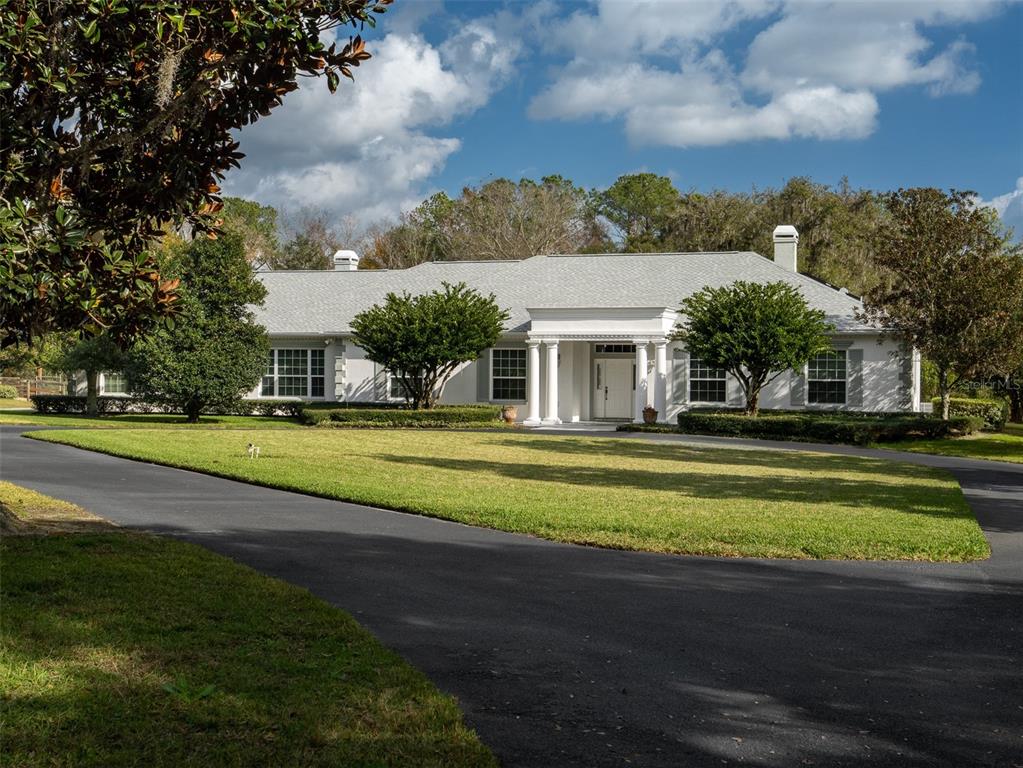 A white, single-story house with a columned entryway and a paved driveway — 7575 NW 90TH AVENUE, OCALA, FL