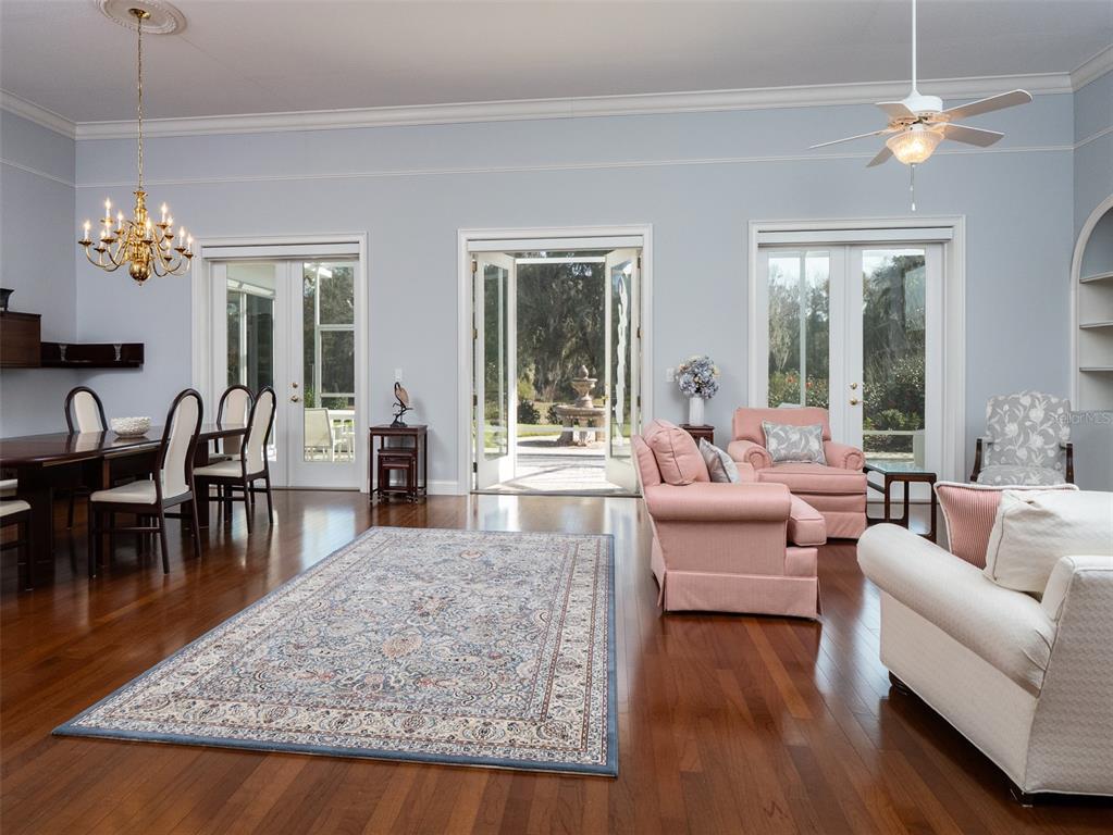 A spacious living and dining room features hardwood floors, light blue walls, and three glass doors — 7575 NW 90TH AVENUE, OCALA, FL