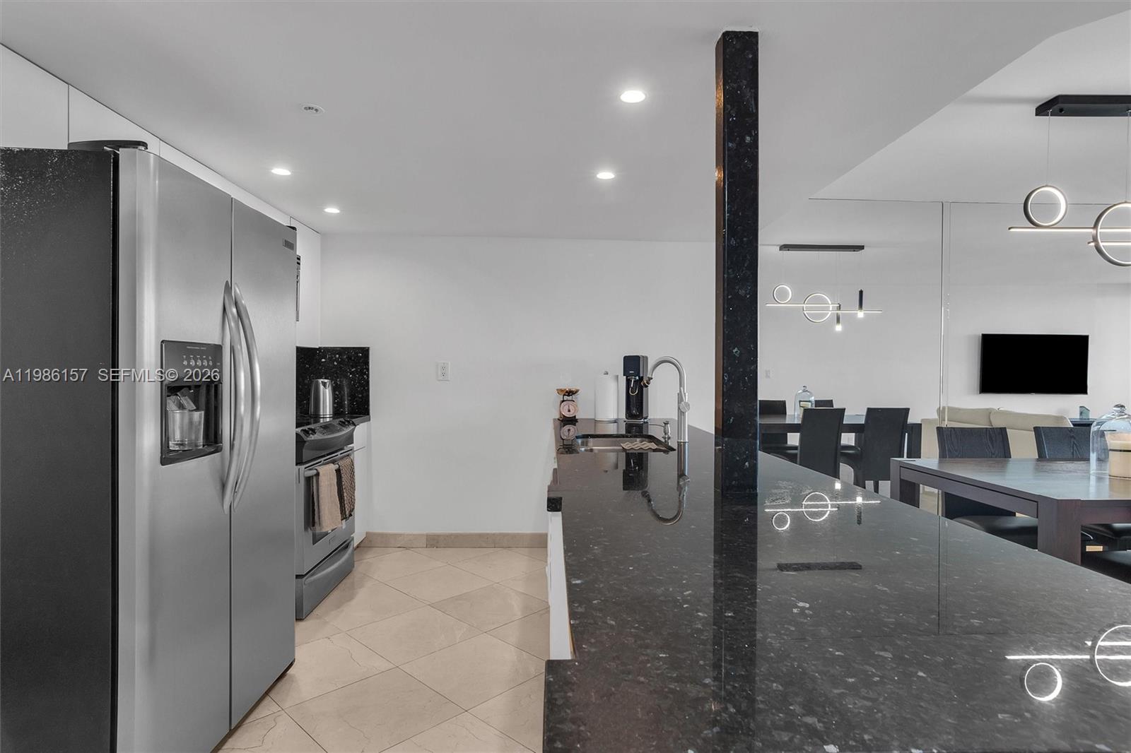 A kitchen features a stainless steel refrigerator, black granite countertops, and a central island — 1717 N Bayshore Dr # 3332, Miami FL 33132, MIAMI, FL