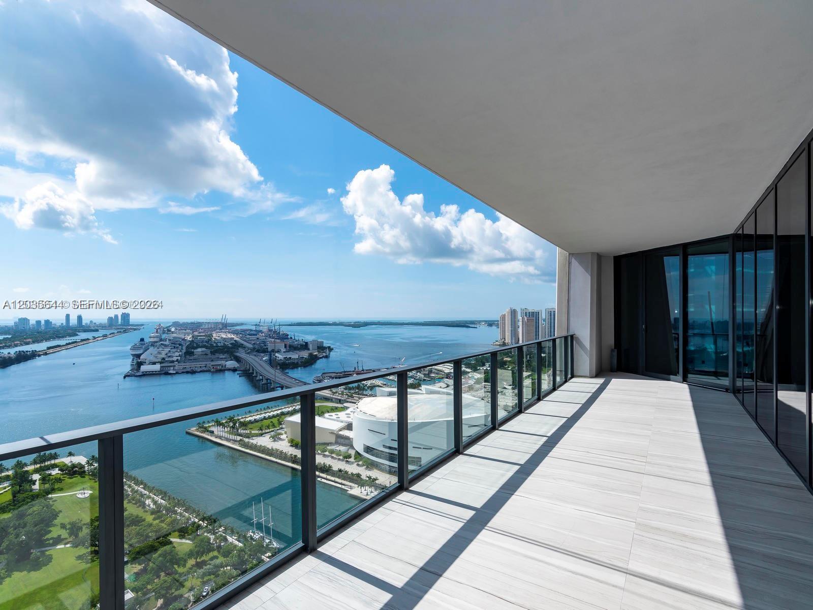 A spacious balcony with glass railings overlooks a bay, a bridge, and city buildings — 1000 Biscayne Blvd # 4802, Miami FL 33132, MIAMI, FL