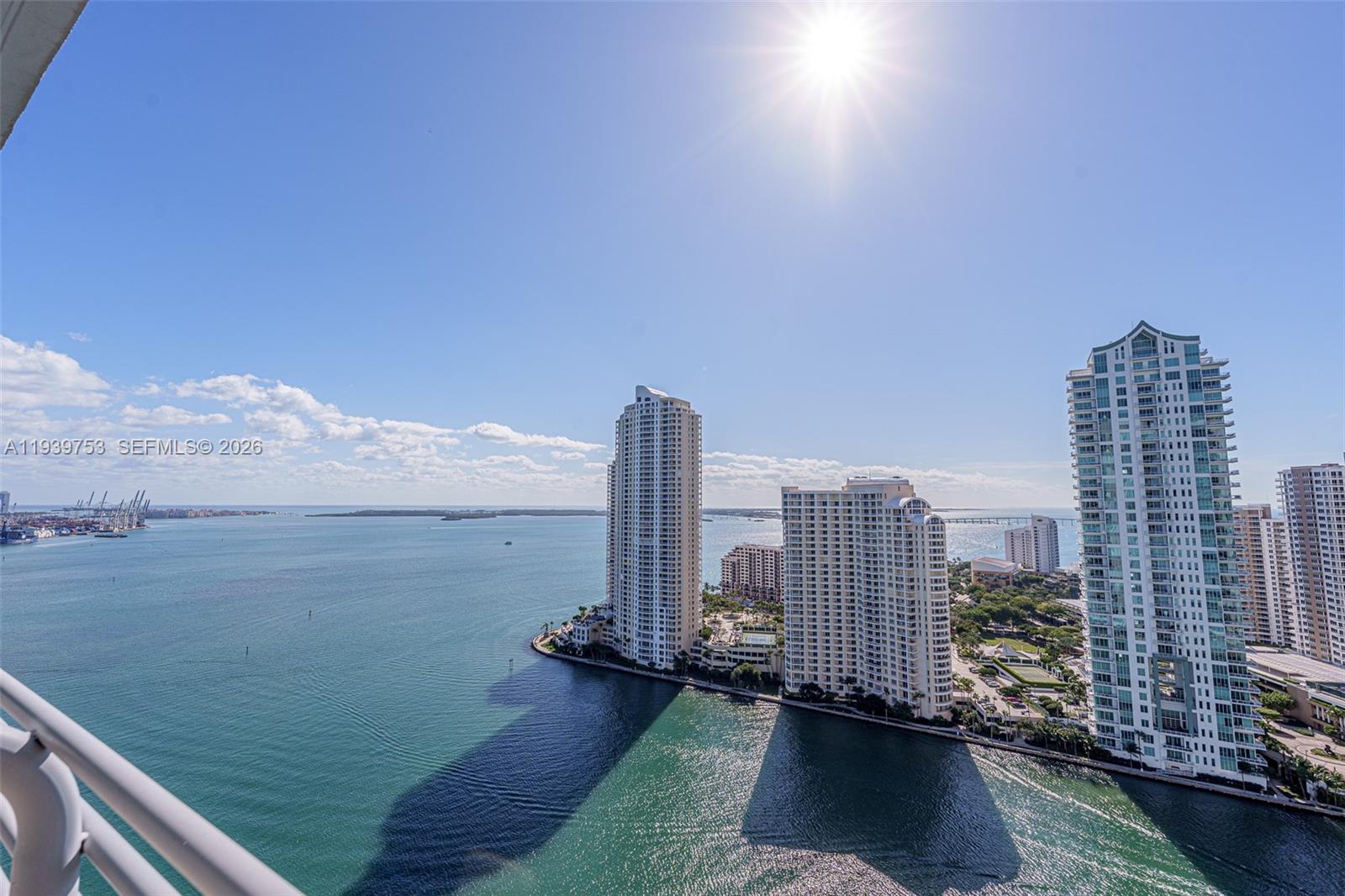 An elevated view shows high-rise buildings situated along a waterfront under a bright sun — 335 S Biscayne Blvd # 3005, Miami FL 33131, MIAMI, FL