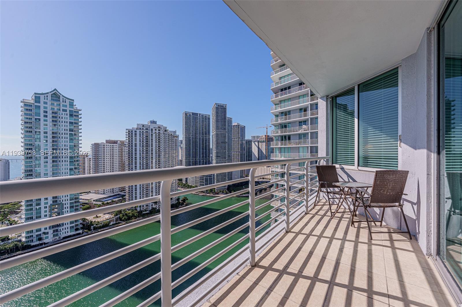A balcony with a metal railing overlooks a canal and a city skyline — 335 S Biscayne Blvd # 3005, Miami FL 33131, MIAMI, FL