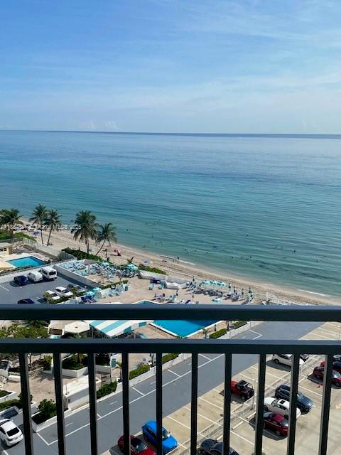 A high-angle view shows a beach, ocean, and parking lot from a balcony — 3180 S Ocean Dr # 1204, Hallandale Beach FL 33009, HALLANDALE BEACH, FL