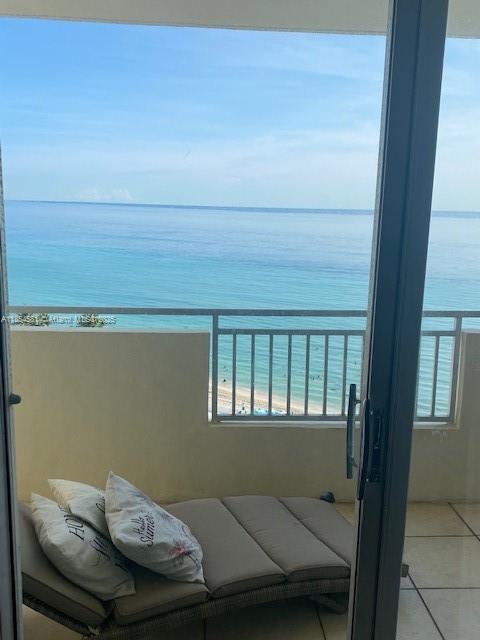 A balcony features a lounge chair with pillows overlooking the ocean and sandy beach — 3180 S Ocean Dr # 1204, Hallandale Beach FL 33009, HALLANDALE BEACH, FL