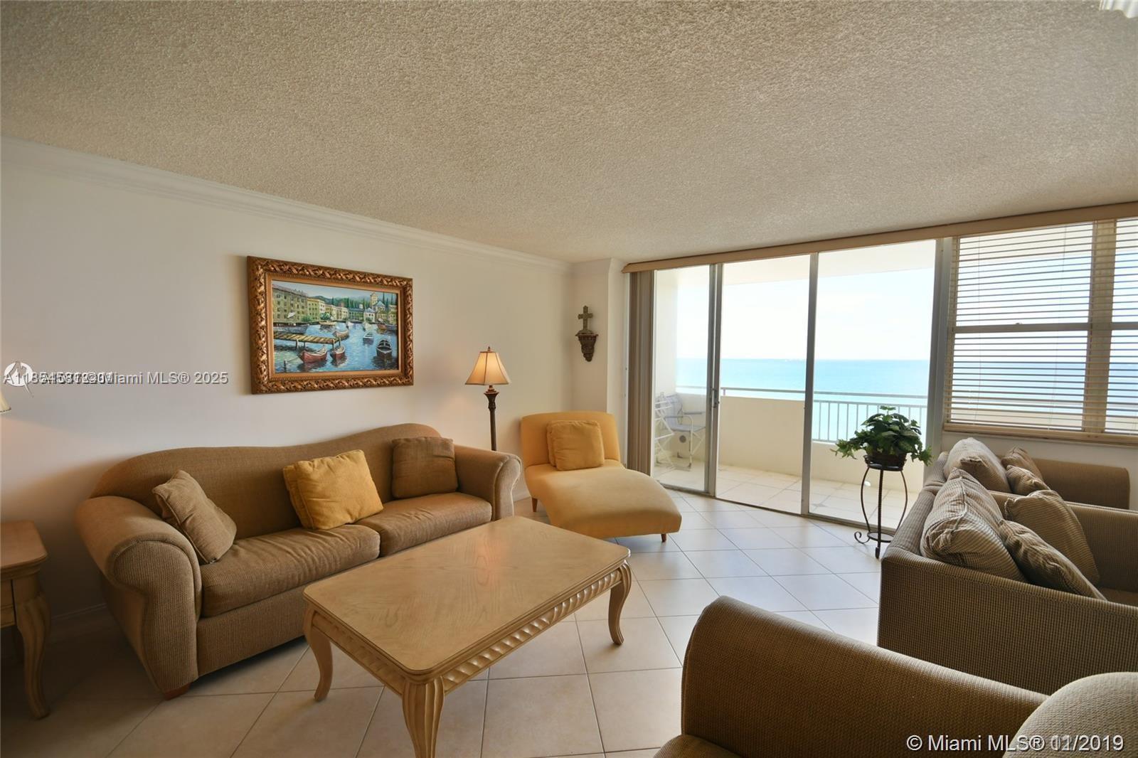 A living room features a beige sofa, yellow chaise, coffee table, and a balcony with ocean views — 3180 S Ocean Dr # 1204, Hallandale Beach FL 33009, HALLANDALE BEACH, FL