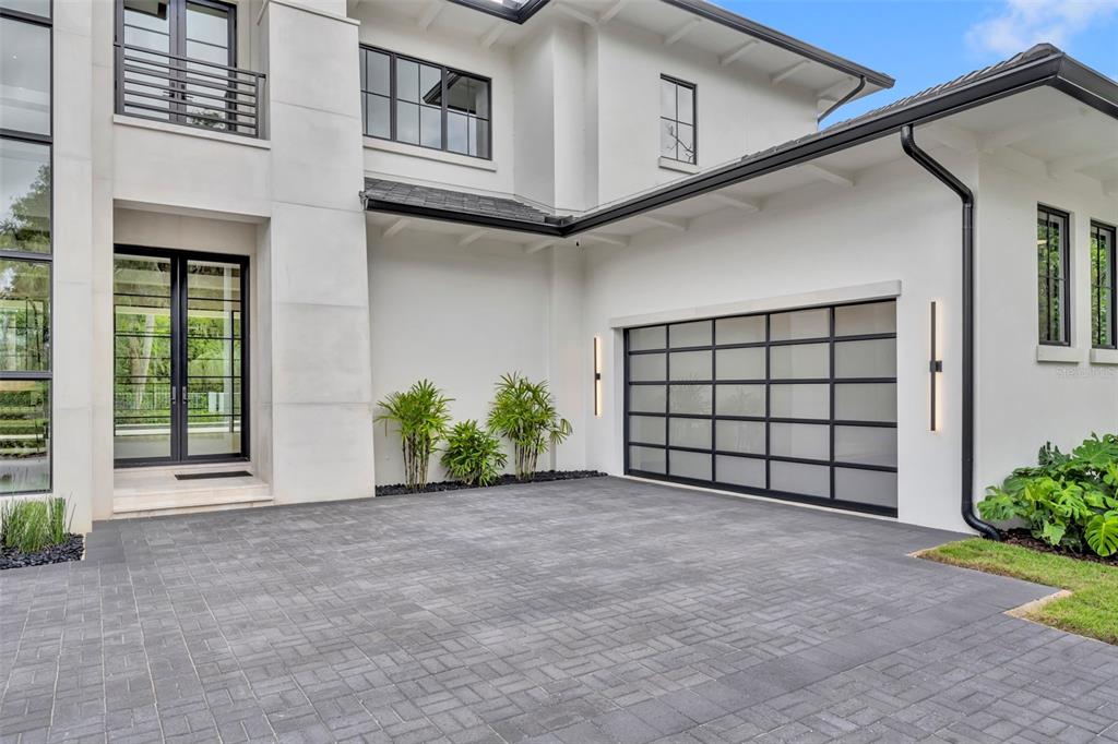 A modern white house exterior features a glass-paneled garage door and a paved driveway — 550 PALMER AVENUE, WINTER PARK, FL