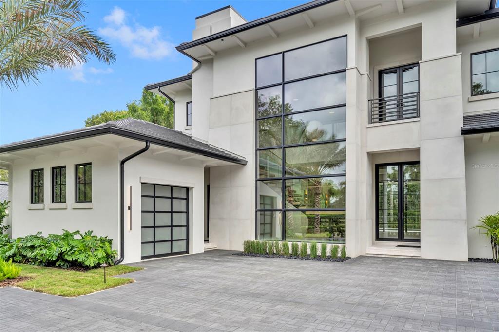 A modern two-story house features a large glass window wall, a garage, and paved driveway — 550 PALMER AVENUE, WINTER PARK, FL