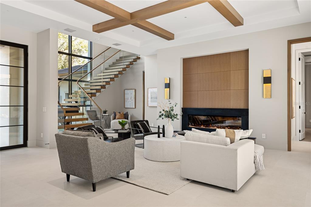 A modern living room features a floating staircase, a fireplace with wood paneling, and beams — 550 PALMER AVENUE, WINTER PARK, FL
