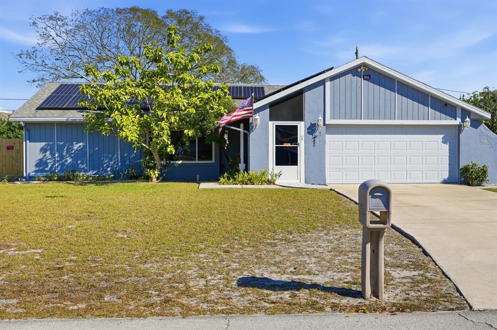 A single-story blue house with solar panels, a front lawn, and a concrete driveway — 934 WILMINGTON DRIVE, DELTONA, FL
