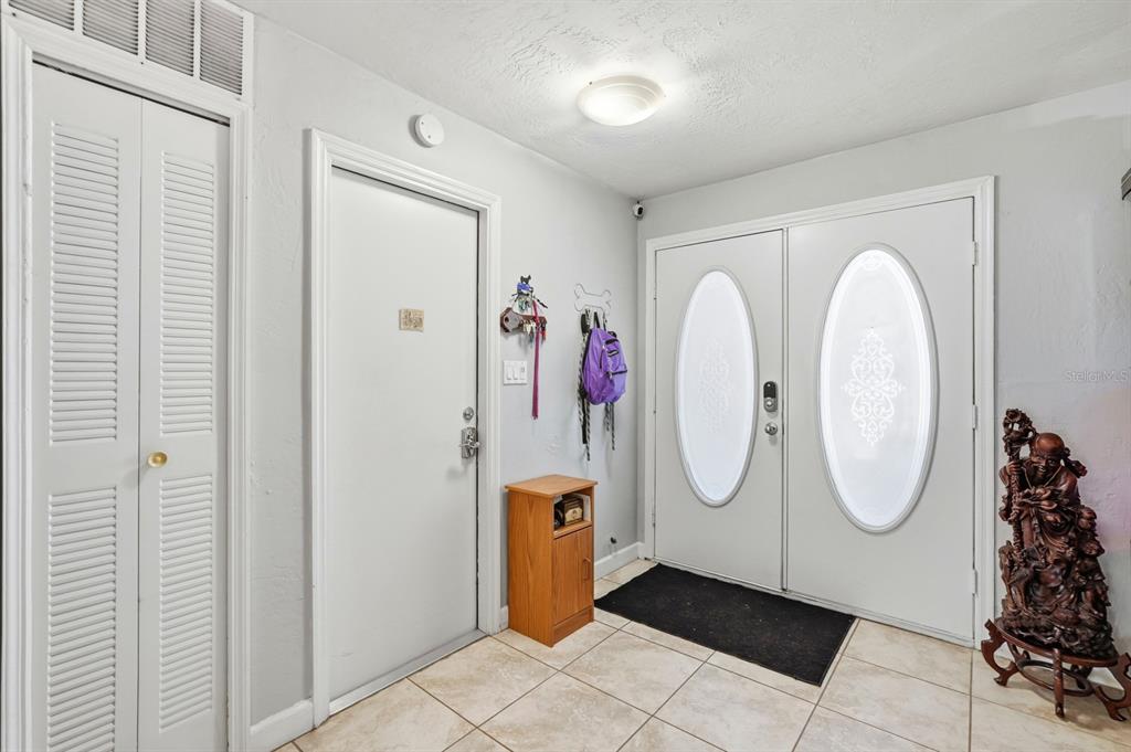 An entryway features tiled flooring, a double front door with glass inserts, and a closet — 934 WILMINGTON DRIVE, DELTONA, FL