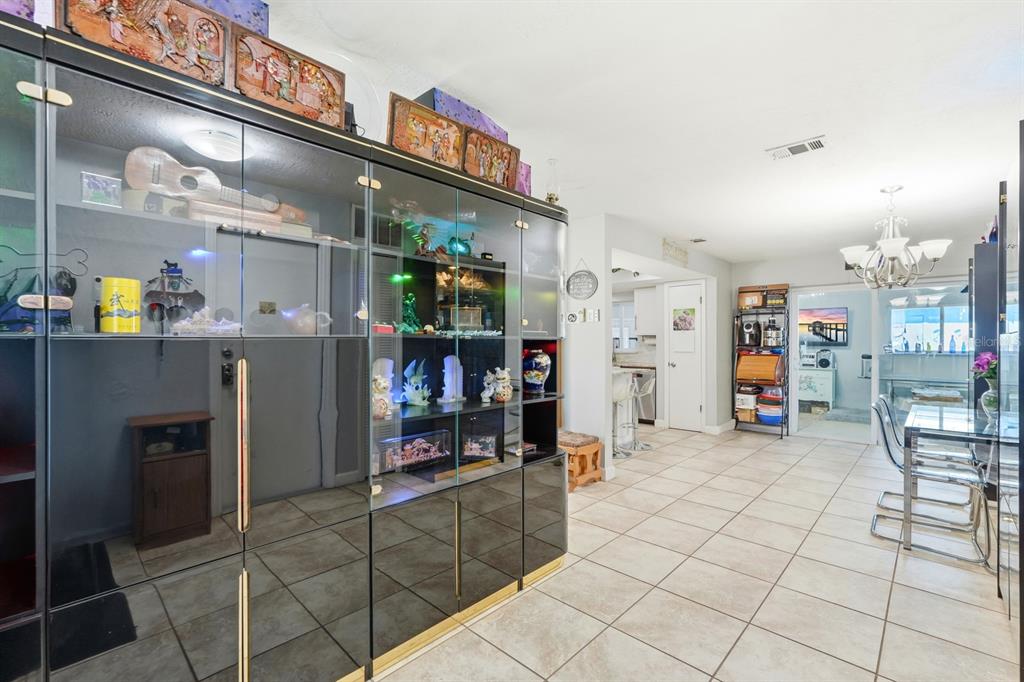A dining area features a large black display cabinet, tile flooring, and a glass table — 934 WILMINGTON DRIVE, DELTONA, FL