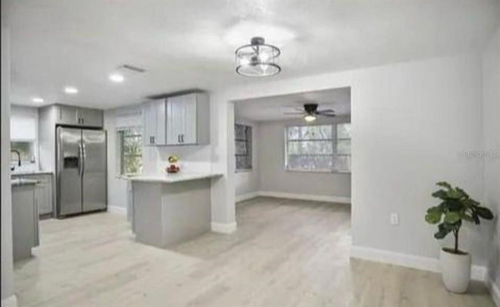 A kitchen with gray cabinets and stainless steel appliances opens into a dining area — 7605 EMBASSY BOULEVARD, PORT RICHEY, FL