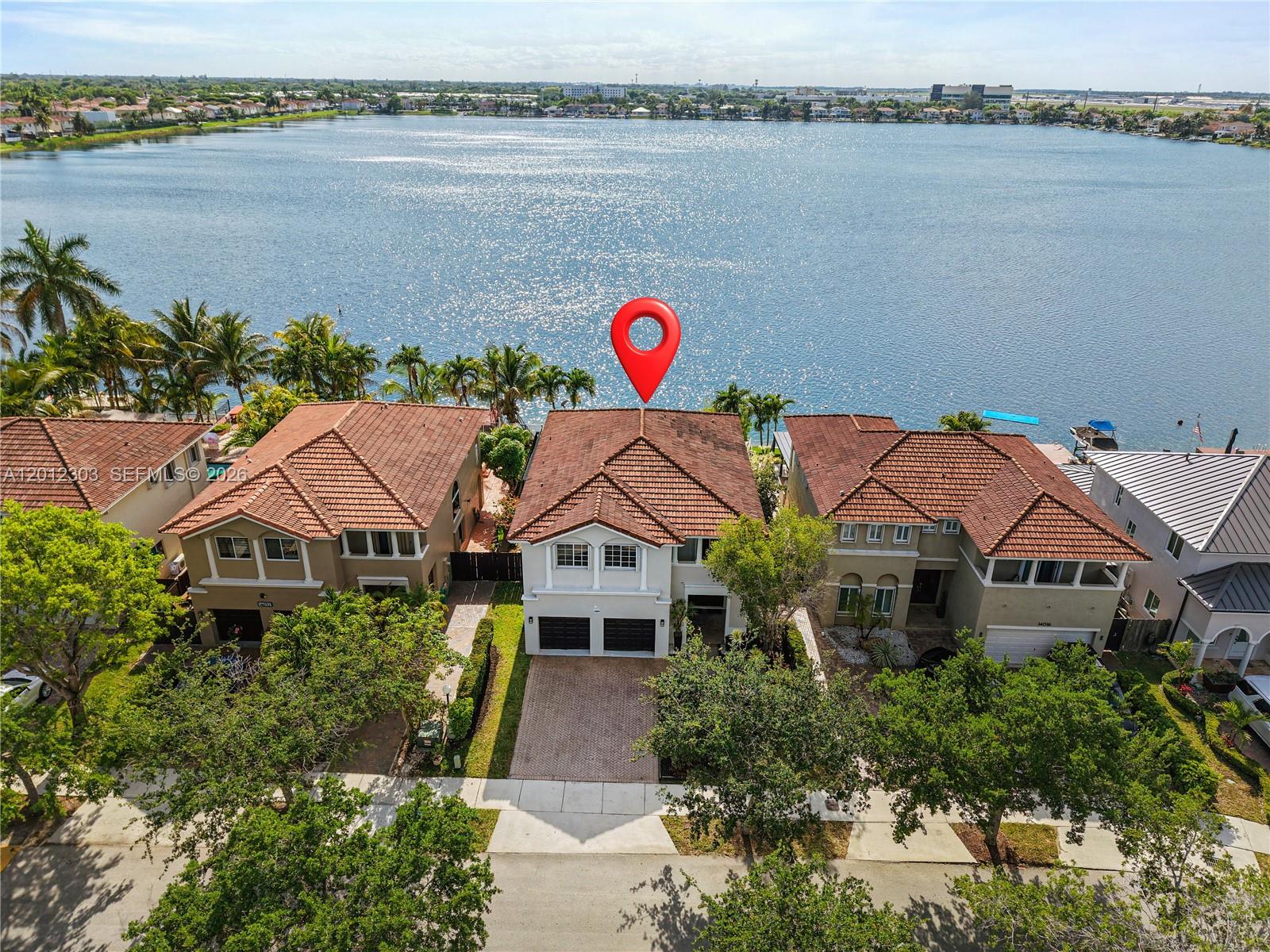 An aerial view shows a two-story house with a red tile roof facing a lake — 14024 SW 132nd Ave, Miami FL 33186, MIAMI, FL