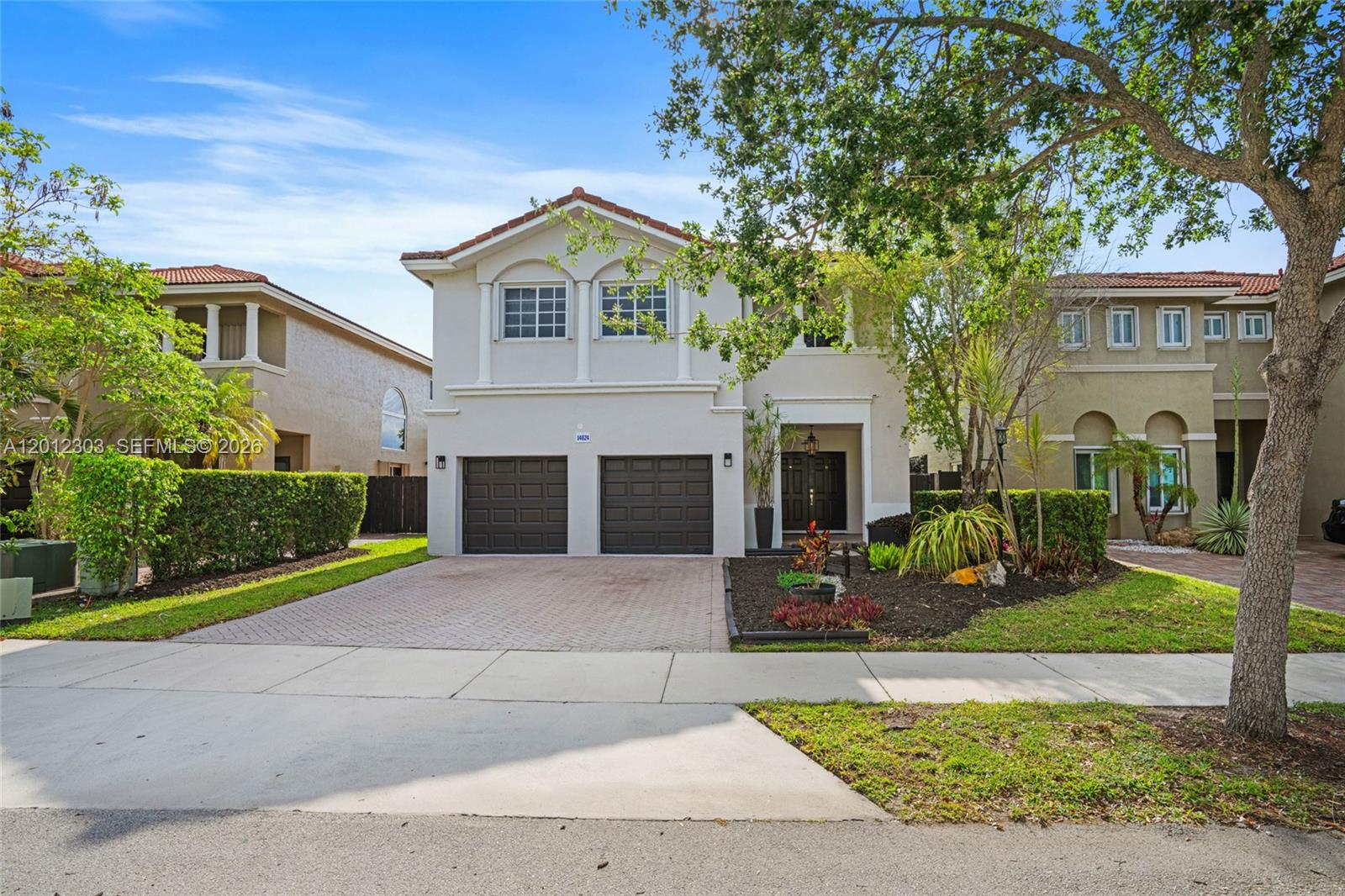 A two-story suburban house features a two-car garage, a paved driveway, and landscaped front yard — 14024 SW 132nd Ave, Miami FL 33186, MIAMI, FL