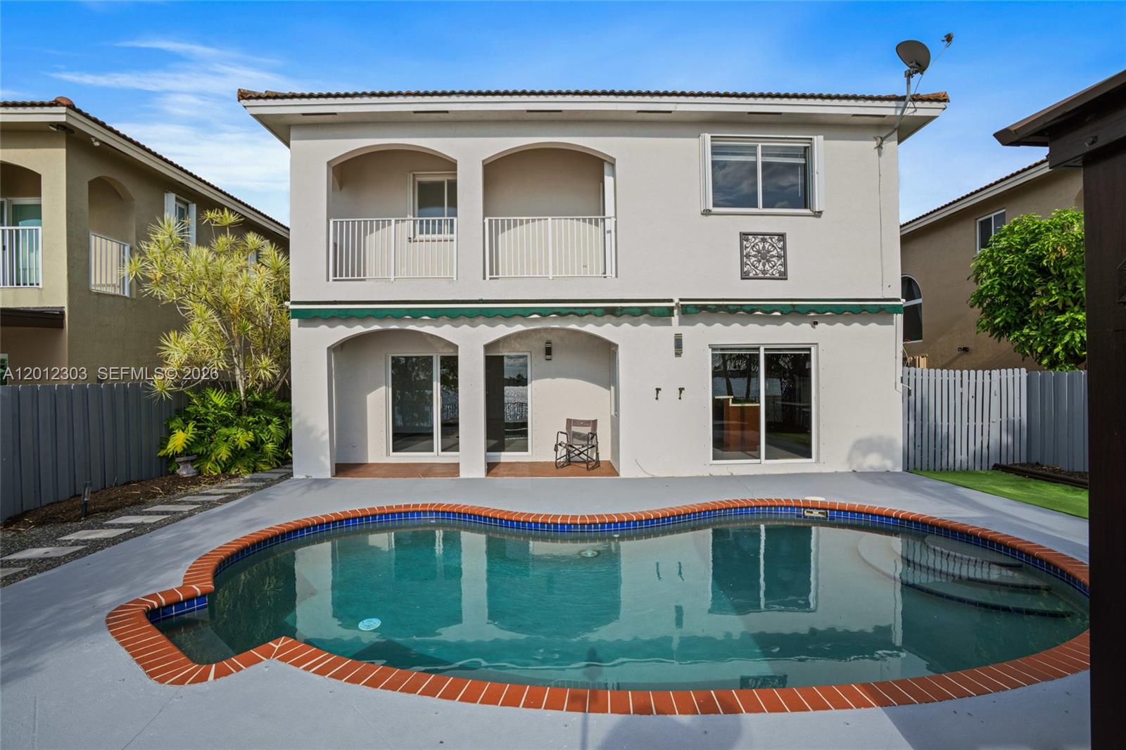 A two-story house exterior features a swimming pool, a covered patio, and a second-floor balcony — 14024 SW 132nd Ave, Miami FL 33186, MIAMI, FL