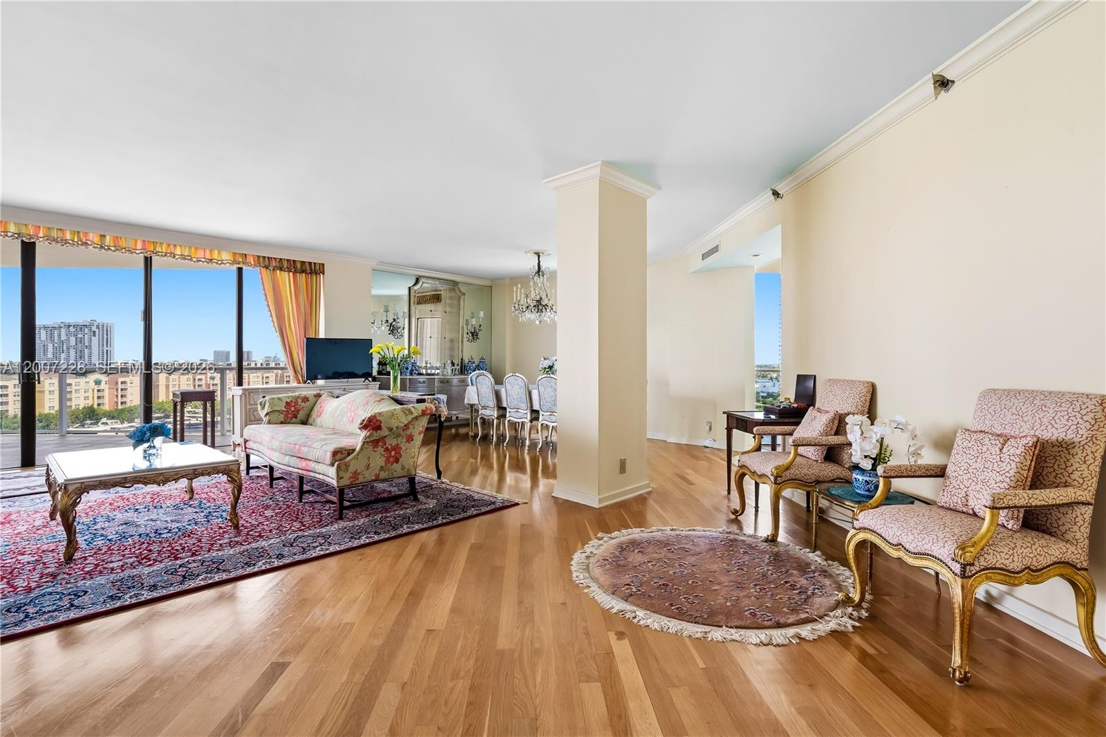 A living and dining area features hardwood floors, a floral sofa, and floor-to-ceiling windows — AVENTURA, FL
