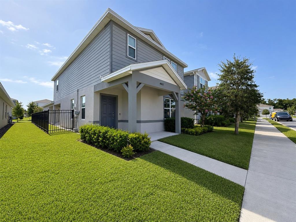 A two-story house with gray siding, a covered front porch, and a manicured lawn — 4083 FEATHER TREE DRIVE, APOPKA, FL