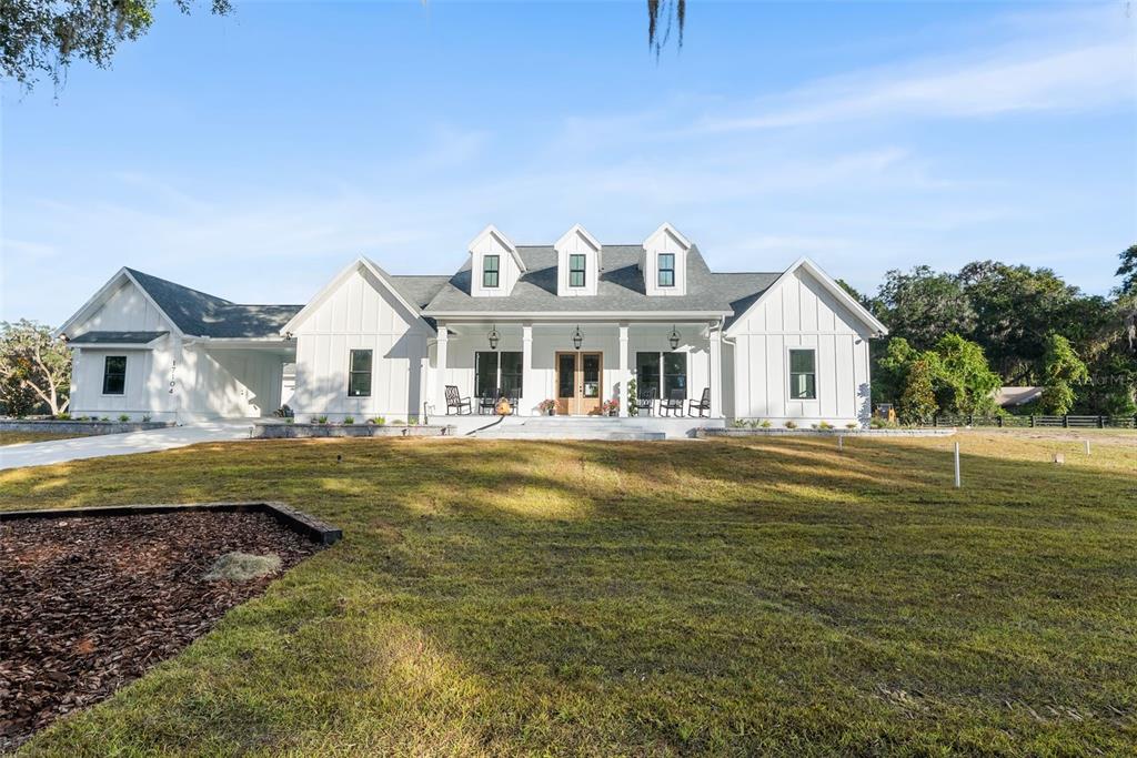 A white farmhouse-style home with a covered front porch and three roof dormers — 17104 SW 11TH COURT, NEWBERRY, FL
