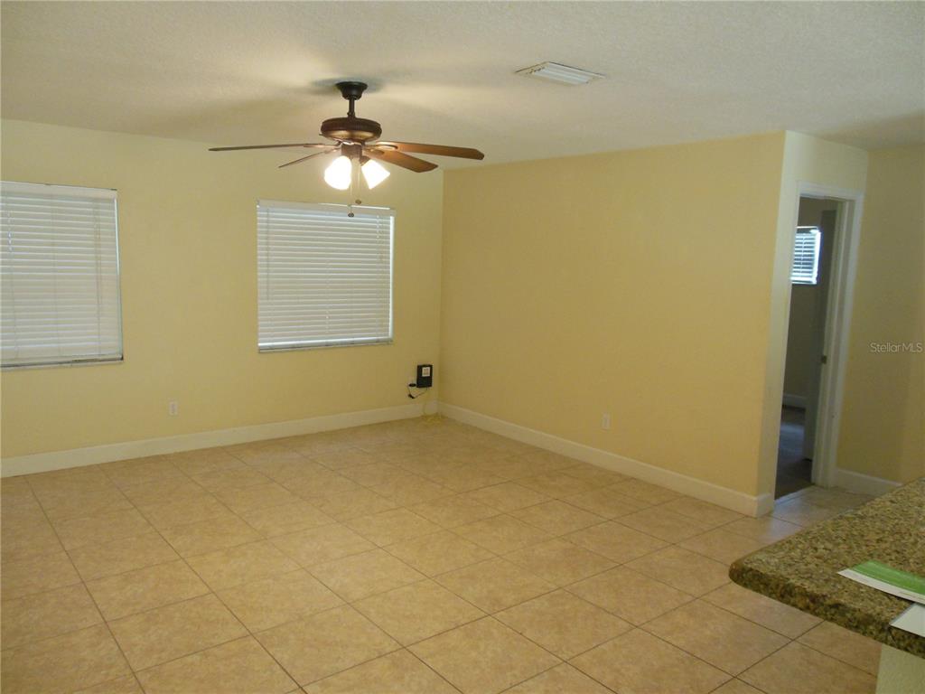 An empty room with yellow walls, tile flooring, a ceiling fan, and two windows — 213 BUTTONWOOD AVENUE, WINTER SPRINGS, FL